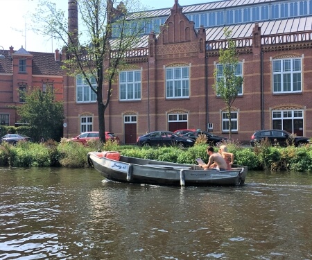 Boot auf einem Amsterdamer Kanal in der Nähe eines alten Fabrikgebäudes<br />
